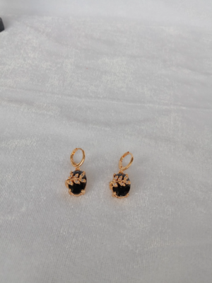 A pair of gold-plated drop earrings with a black CZ stone and a delicate gold leaf design with smaller stones on a white fabric background. 5.jpg: A pair of gold-plated drop earrings with a pi